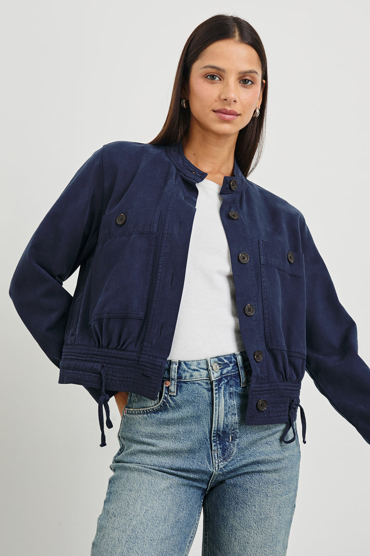 Alma Jacket with Button Closure, Mandarin Collar, Two Large Chest Button Patch Pockets and a Drawcord at the Hem in Navy Colorway - Front View Featured on Model