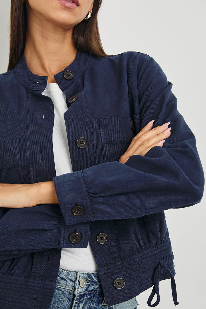 Alma Jacket with Button Closure, Mandarin Collar, Two Large Chest Button Patch Pockets and a Drawcord at the Hem in Navy Colorway - Front View Featured on Model