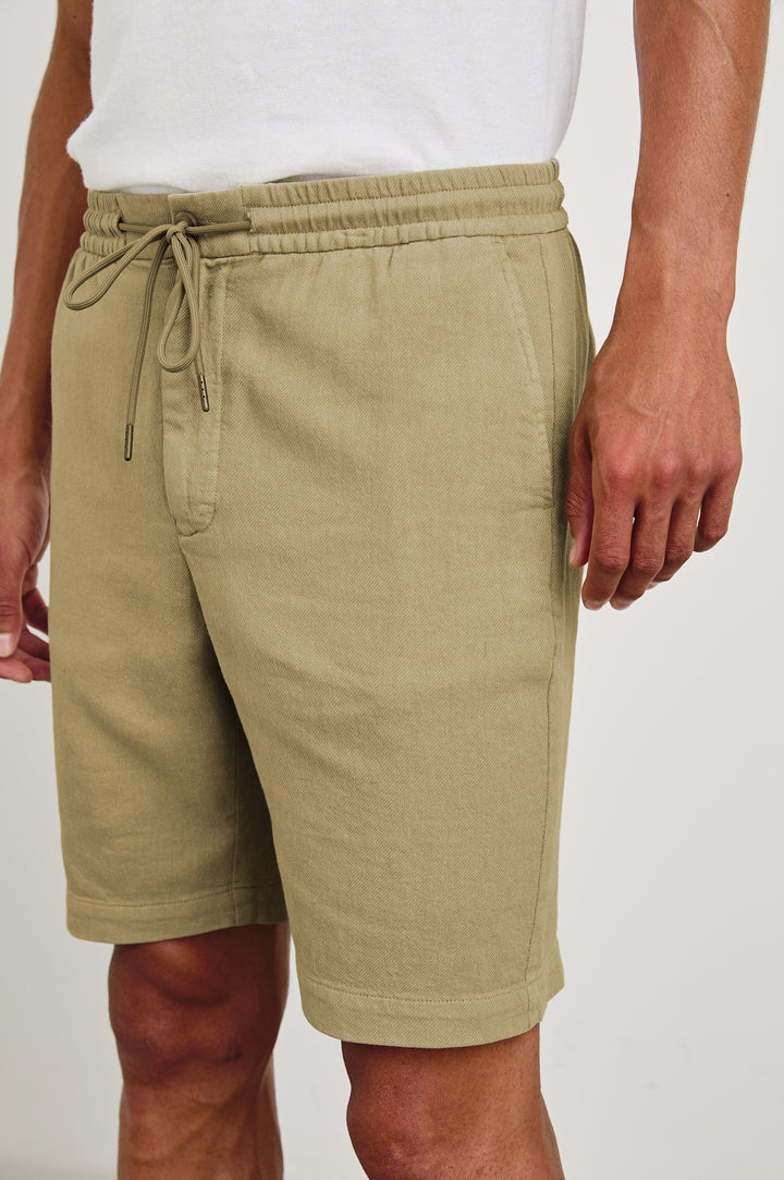 Archer long length cotton short with adjustable drawstring and front button closure in True Khaki - close up of details on model