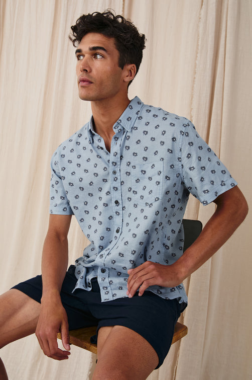 Carson linen short sleeve button down with a collar and floral pattern in Daisy Toss Celestial - styles front view on model, sitting