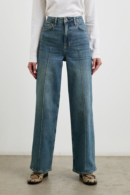 Getty Pintuck Wide Leg Denim Pants with a Vertical Center Front and Back Leg Seam, Belt Loops, Two Front Pockets and Two Back Patch Pockets in Authentic Blue Colorway - Front View Featured on Model