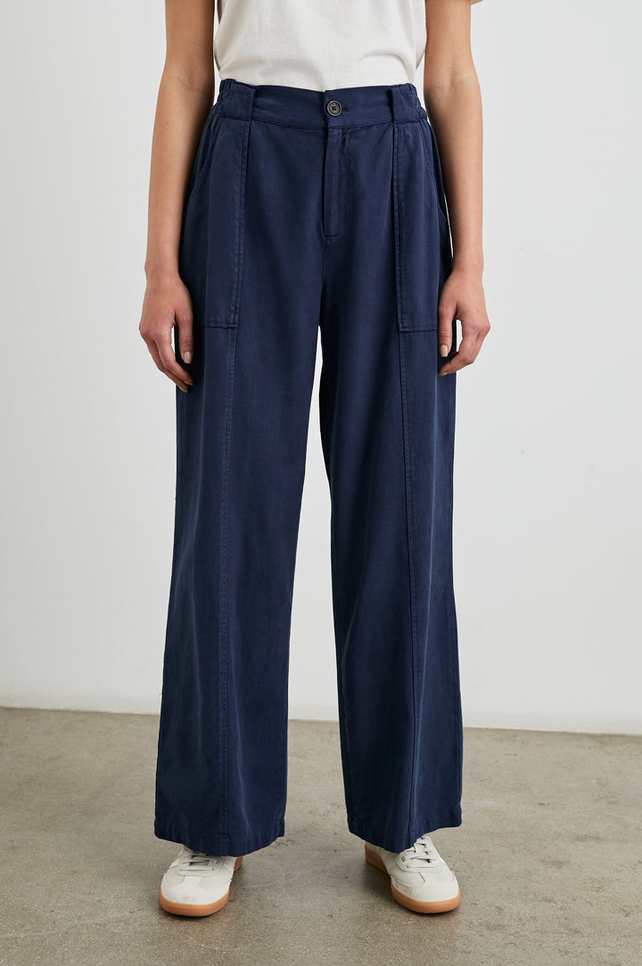 Greer Pants with Two Large Front Pockets, Two Back Welt Pockets and Vertical Seams Down the Front and Back Legs in Navy Colorway - Front View Featured on Model 