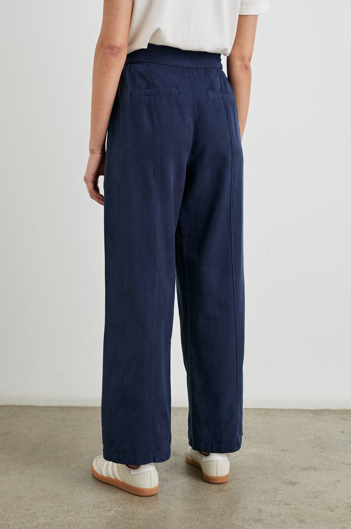 Greer Pants with Two Large Front Pockets, Two Back Welt Pockets and Vertical Seams Down the Front and Back Legs in Navy Colorway - Back View Featured on Model 