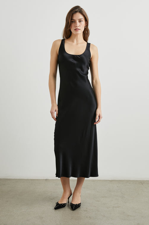 Kailani Sleeveless Midi Dress with Shoulder Straps, a Scoop Neck and Side Slit to the Knee in Black Satin Crepe Colorway - Front Full Body View Featured on Model