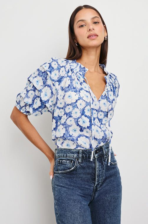 Paris Short-Sleeve Top with Shirred Collar, V-neckline with Ties, Deep Pleats on Sleeves and Elastic at the Sleeve Opening in Blue Floral Colorway, Blues and White - Front Tucked View Featured on Model