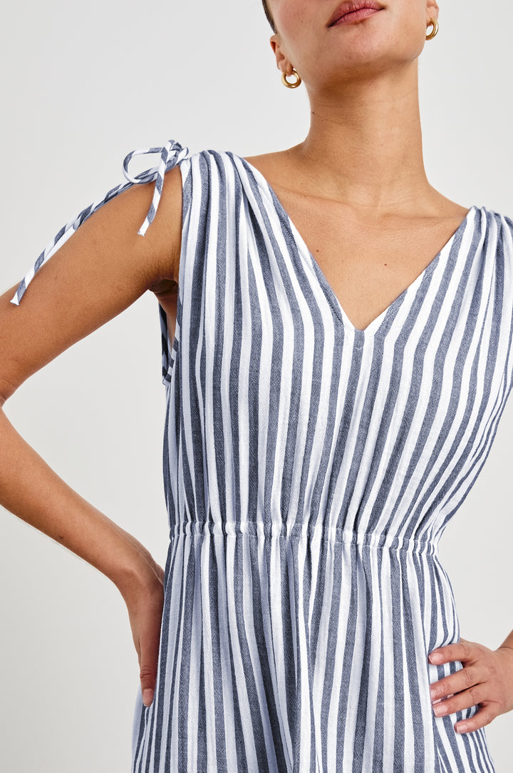 Detailed, zoomed view of model wearing a tiered midi dress featuring blue and white vertical stripes. Suzette dress features an elasticated waist and customizable shoulder straps.