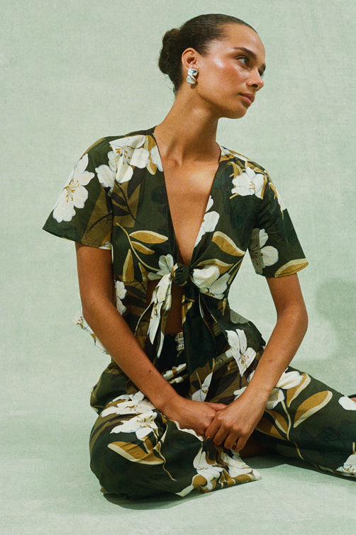 Tia mid sleeve, lightweight top with front tie closure in Plumerias tropical floral print - on model sitting on floor