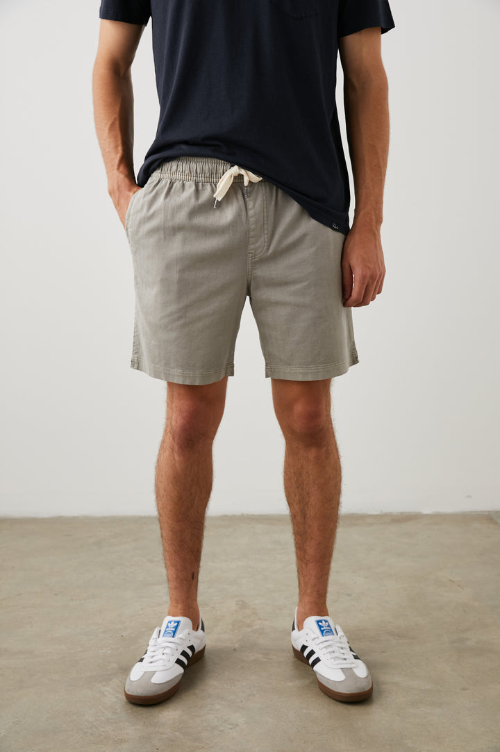 Cruz Shorts with a Drawstring Waist, Two Front Pockets, Two Back Button Flap Pockets in Washed Grey Colorway - Front View Featured on Model 